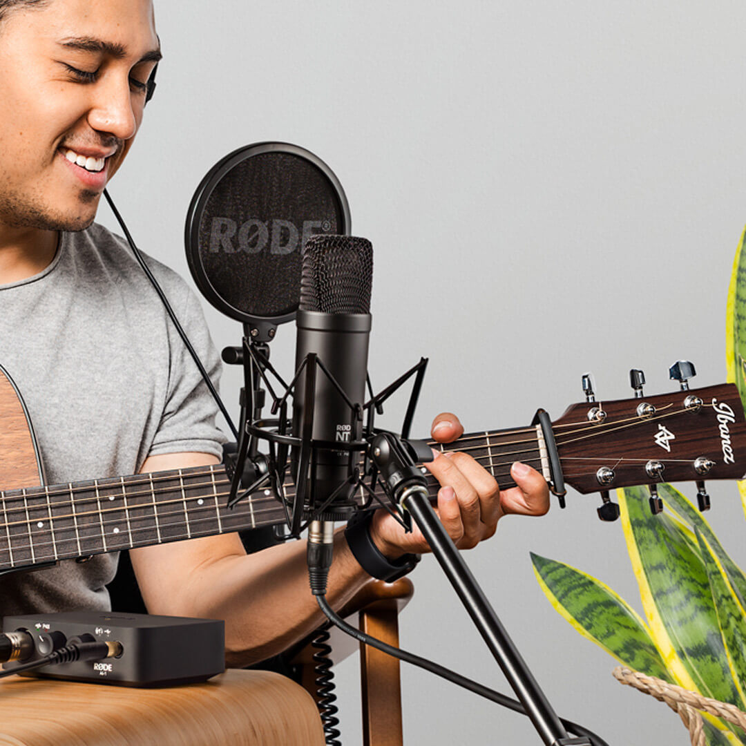 Man recording vocals and acoustic guitar with NT1 on SM6 attached to microphone stand